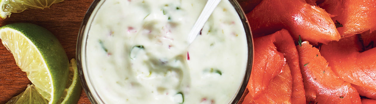 Alt Text: Top down view of small clear bowl of Wasabi Lime Sour Cream with a spoon dipped in