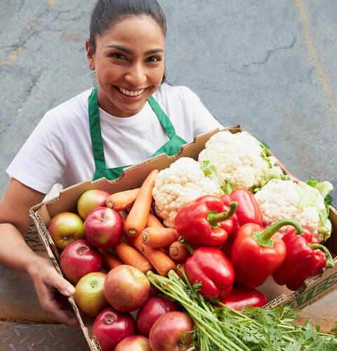 Woman holding surplus produce in box from grocery store