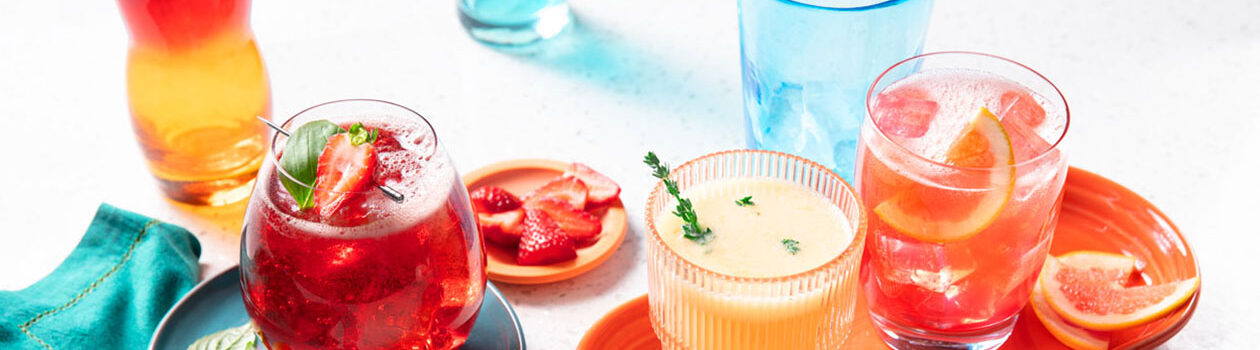 Clear tumbler filled with a lemon iced tea, lemon juice, strawberry soda and basil leaf mocktail, garnished with a strawberry.