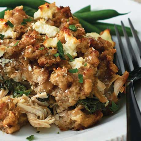 Leftover turkey stuffing casserole next to a side of blanched green beans sitting on a white dinner plate.