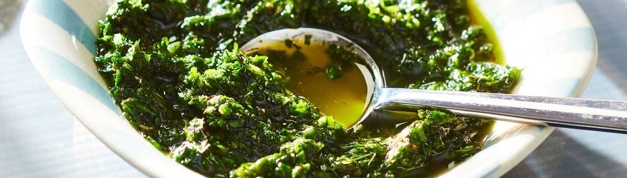 White and blue striped bowl filled with a fresh herb green sauce.