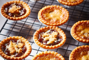 Cooling rack of butter tarts and mince tarts with sweet crumble on top