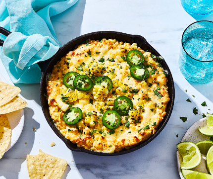 Mexican street corn-inspired party dip in a cast iron serving pan on summer table