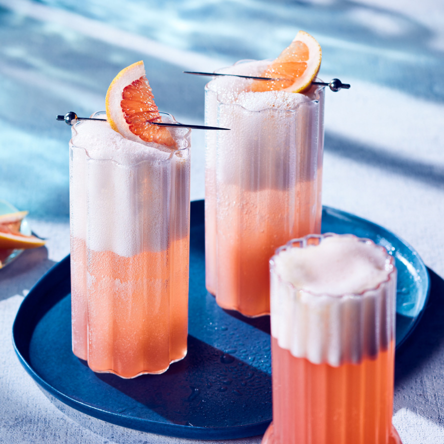 Two tall glasses with bubbly sparkling pink paloma-style cocktail