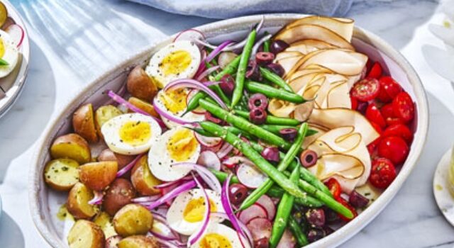 platter of niçoise salad with beans, hard-boiiled eggs, potatoes, radish, tomatoes, olives and cured meats