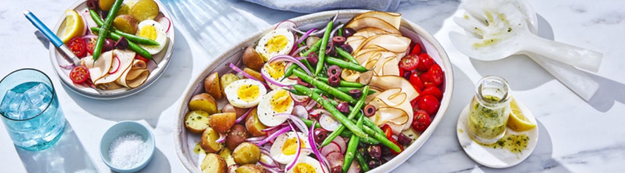 platter of niçoise salad with beans, hard-boiiled eggs, potatoes, radish, tomatoes, olives and cured meats